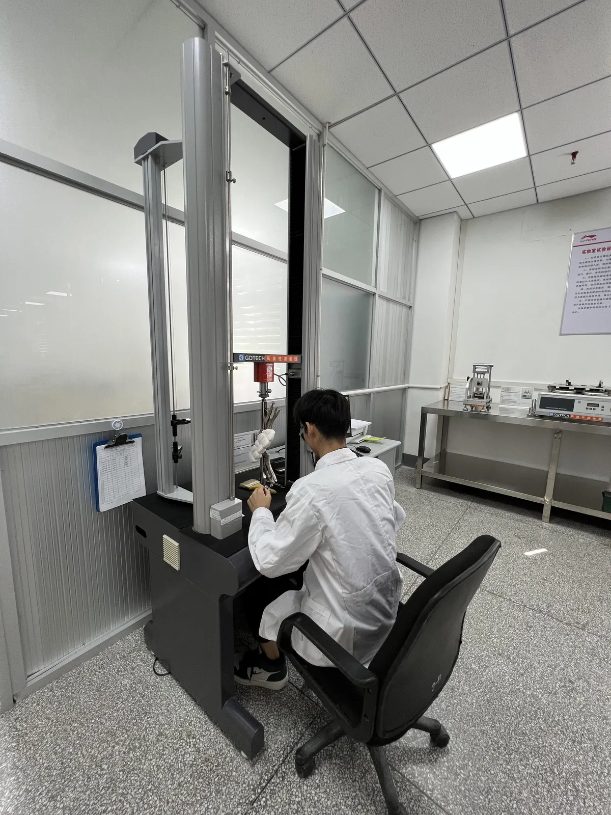 Technician running a strength test on a GOTECH universal testing machine