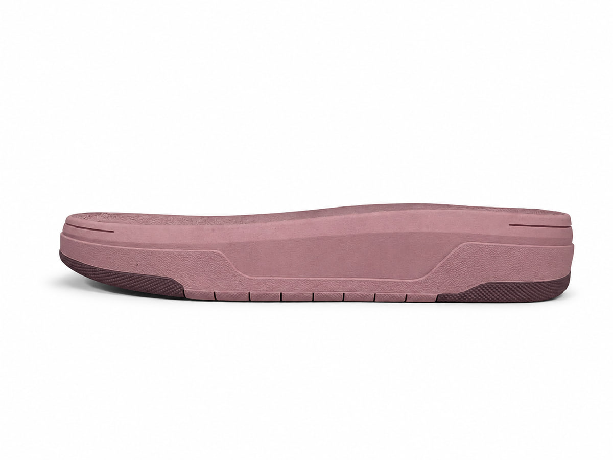 Pink moulded sole unit seen from the side, foamed midsole over a darker rubber outsole edge