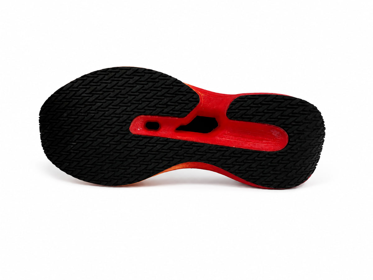 Underside of the same sole, with a black herringbone tread and a raised red midfoot bridge