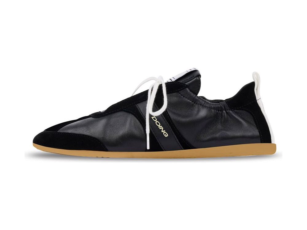 OEM/ODM black leather low-top sneaker with a gathered elasticated upper, black suede toe wrap and heel, white round laces and heel pull loop over a gum midsole, manufactured by DOING Footwear